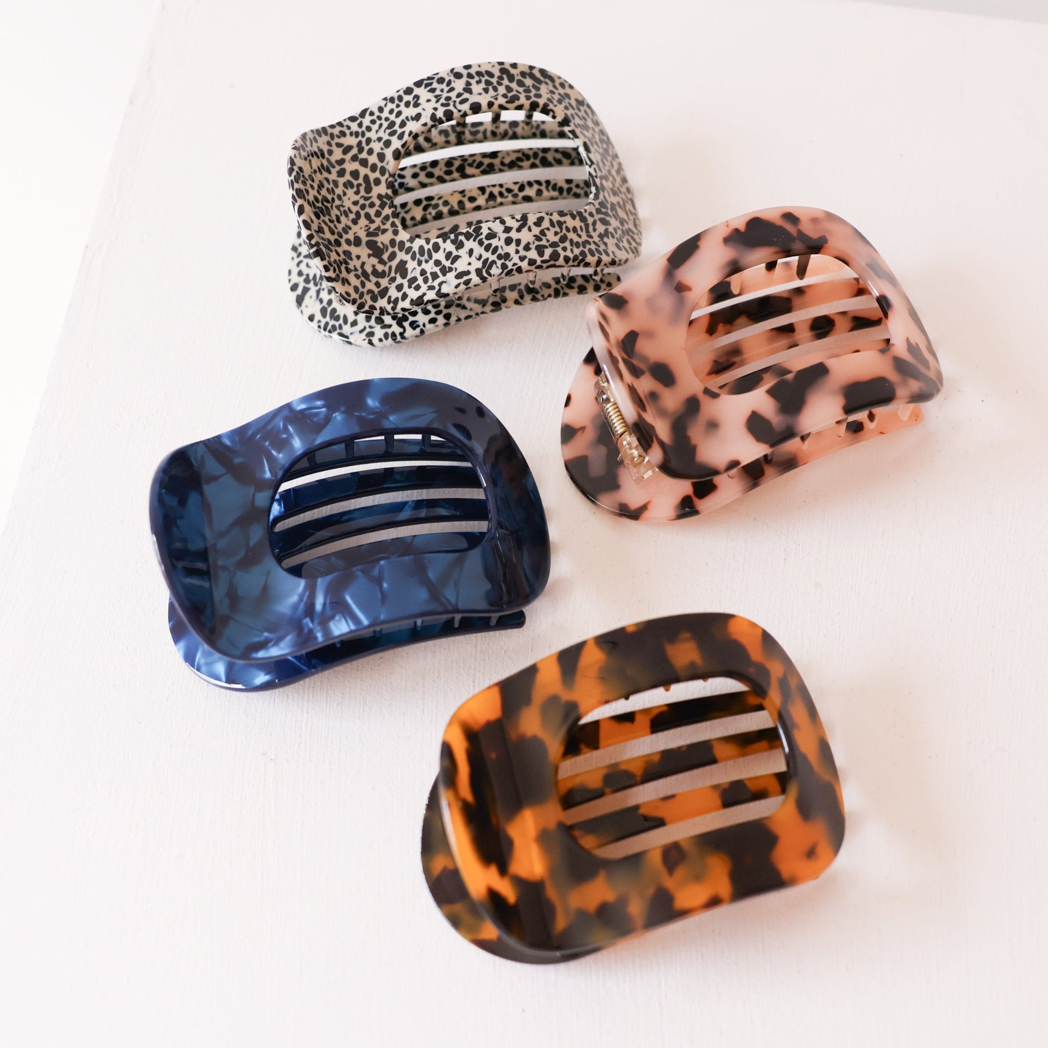 Four colorful hair clips with leopard print pattern on a white background