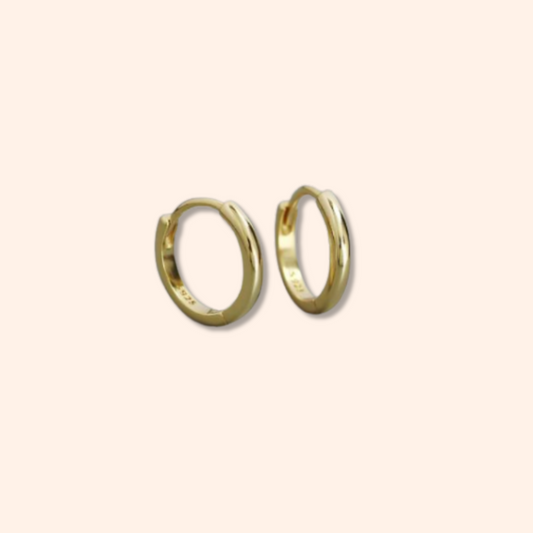 Gold hoop earrings on a beige background