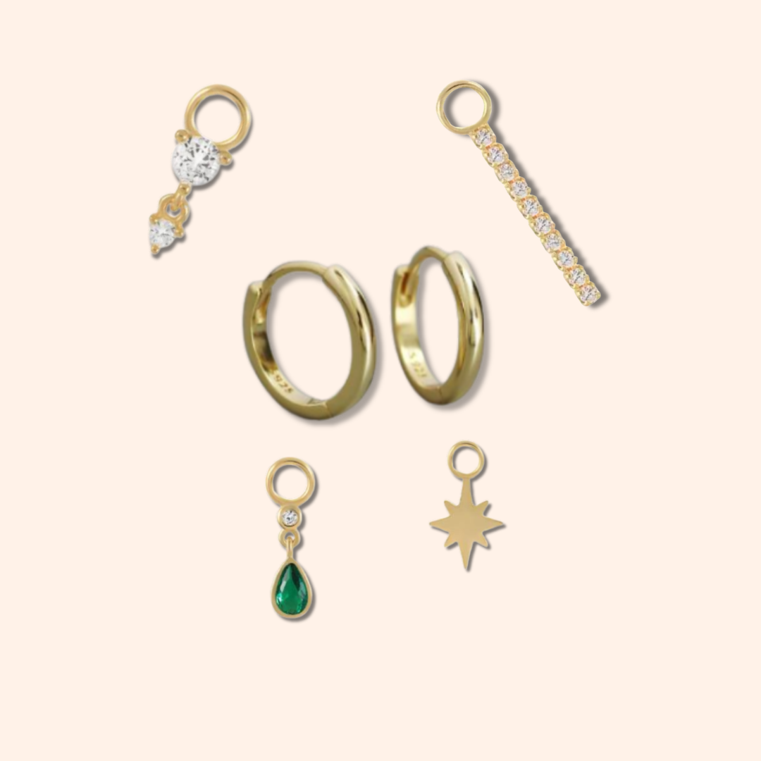 Collection of gold jewelry pieces including rings and pendants on a beige background