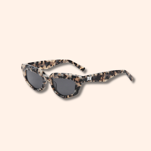 Sunglasses with tortoiseshell frame and dark lenses on a beige background
