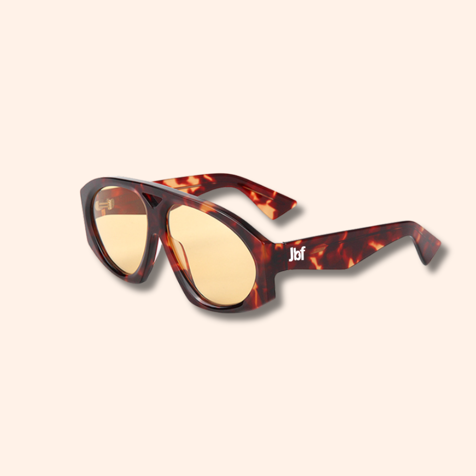 Sunglasses with tortoiseshell frame and yellow lenses on a beige background