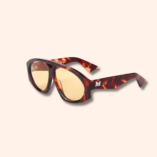 Sunglasses with tortoiseshell frame and yellow lenses on a beige background