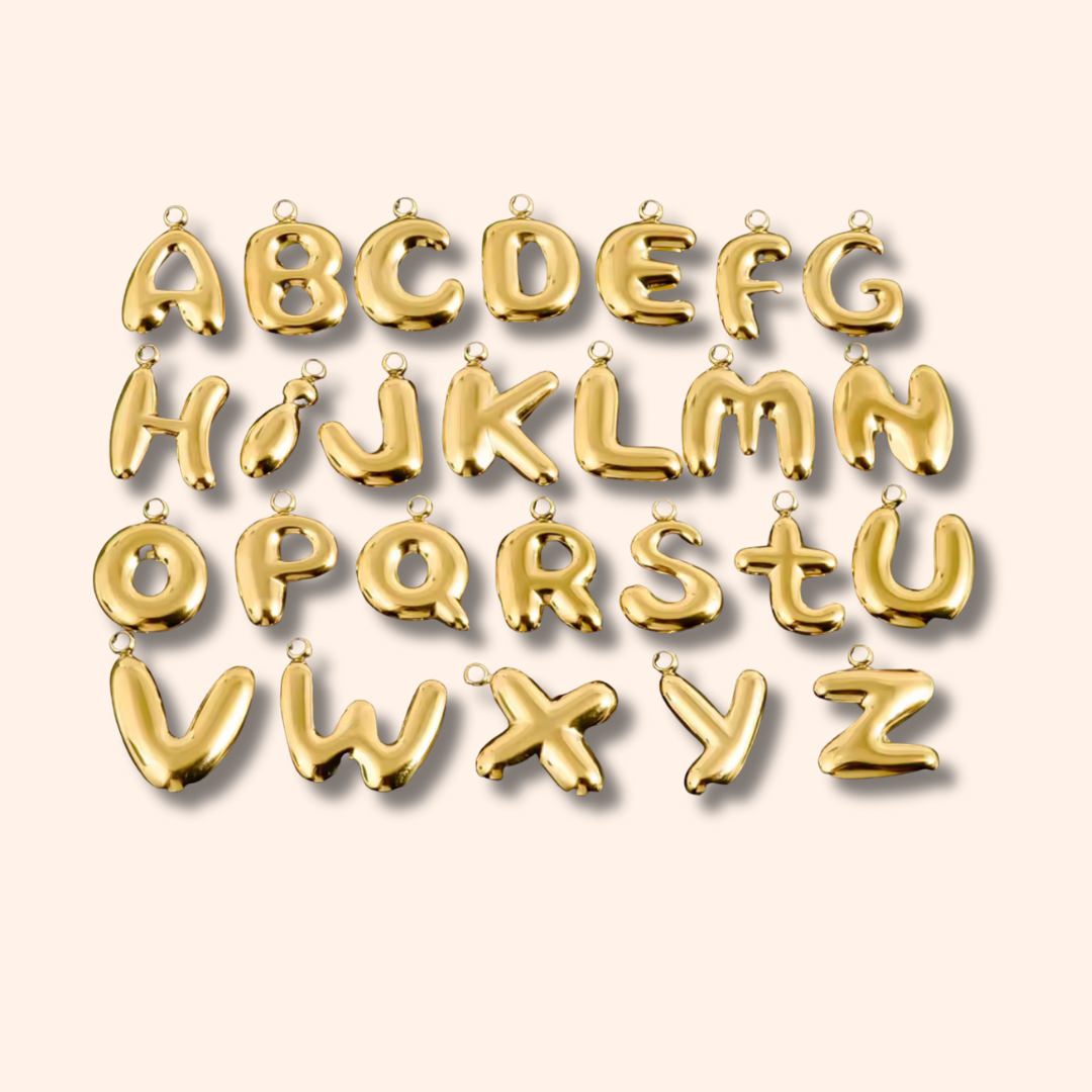 Gold letter pendants spelling out 'P' on a beige background