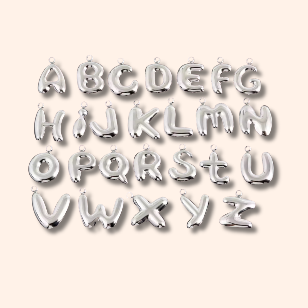 Silver letter balloons spelling out the alphabet on a light pink background