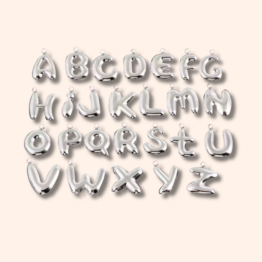 Silver letter balloons spelling out the alphabet on a light pink background
