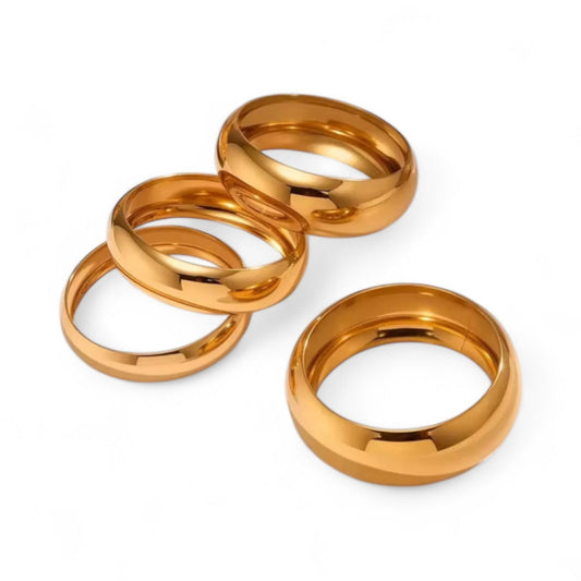Four gold Bangles stacked on a white background