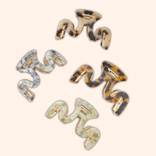 Set of five hair clips with tortoiseshell and silver designs on a beige background