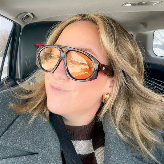 Person wearing sunglasses and a coat inside a car