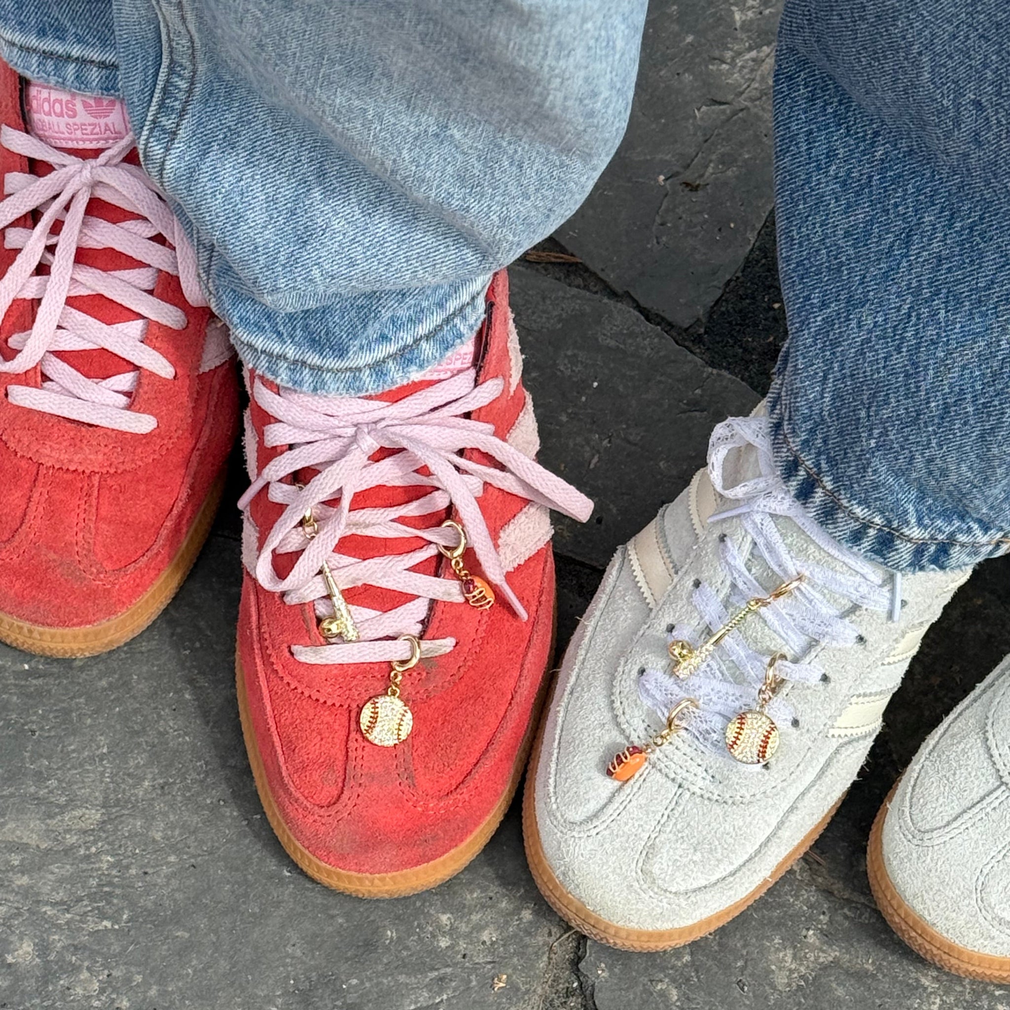 Two pairs of sneakers, one red and one white, on a stone surface.