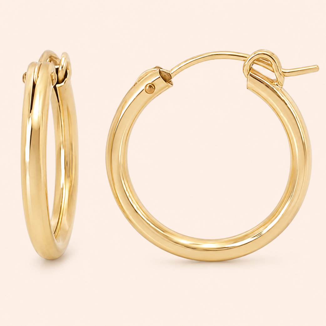 A pair of polished gold hoop earrings shown on a clean, solid pale pink background. One earring is displayed from a side profile view, and the other is shown from a front-facing angle highlighting its post and back clasp.