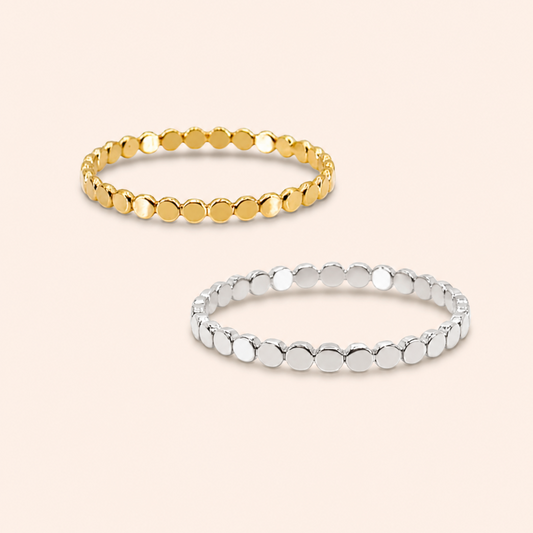Two beaded metal rings, one gold and one silver, displayed on a light beige background.