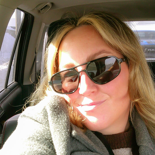 Person wearing sunglasses and a coat inside a vehicle