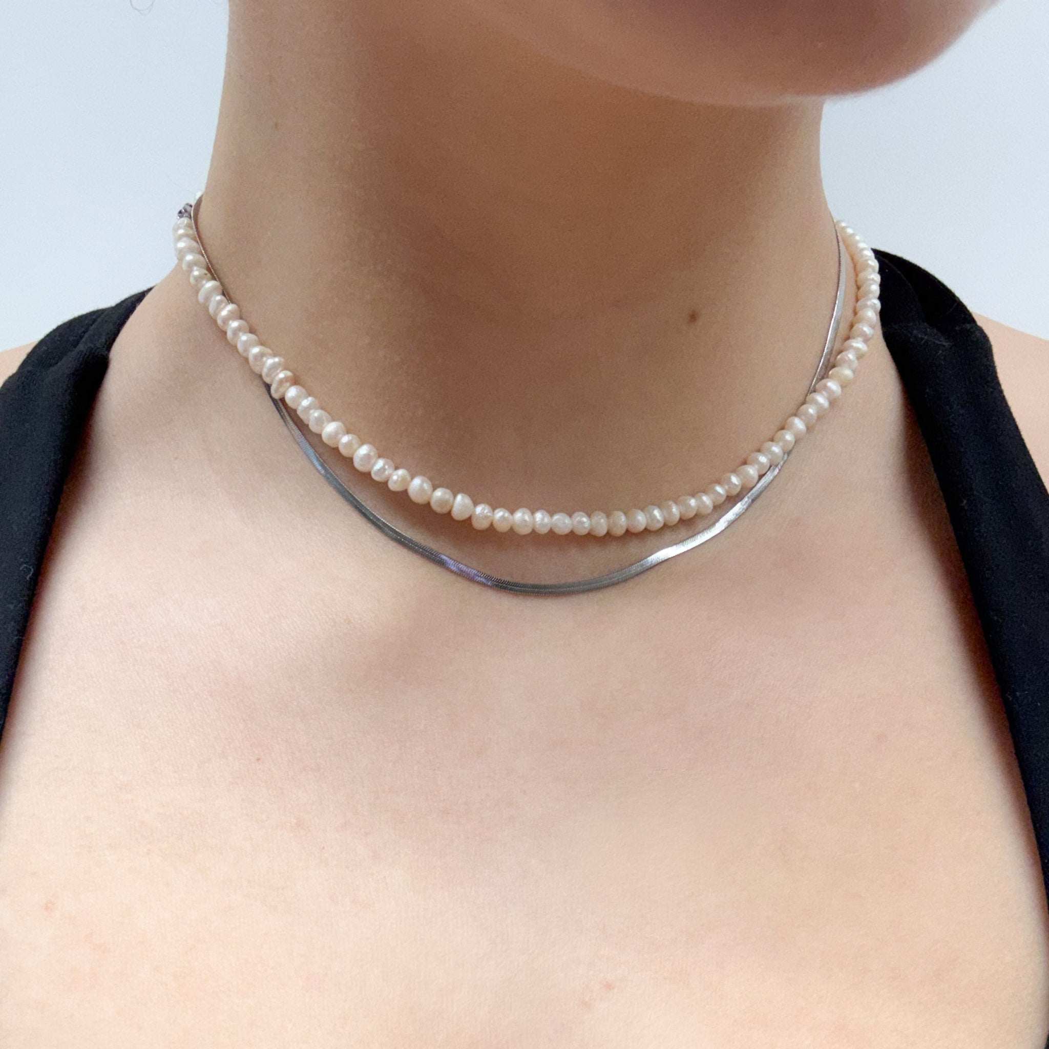 Pearl necklace worn by a person on a plain background