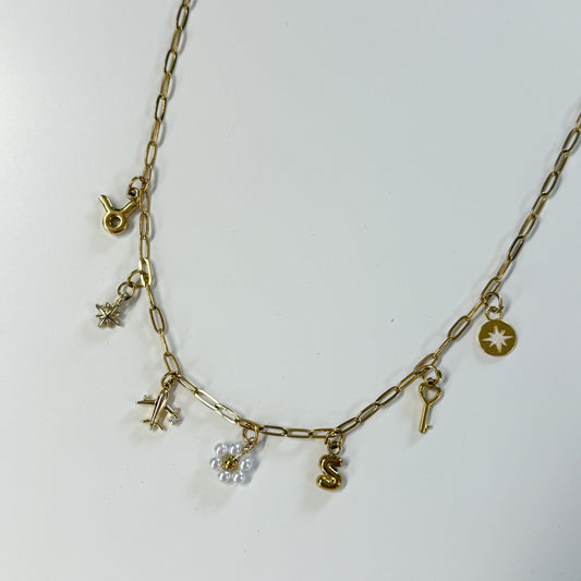 Gold necklace with various charms on a white background