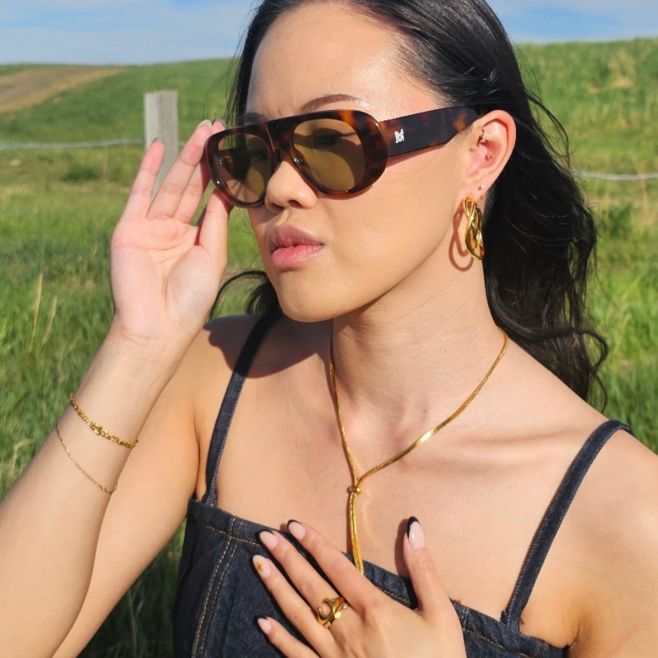 Woman wearing sunglasses and a denim dress in a field