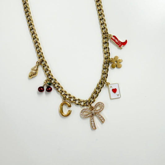 Gold chain necklace with various charms on a white background