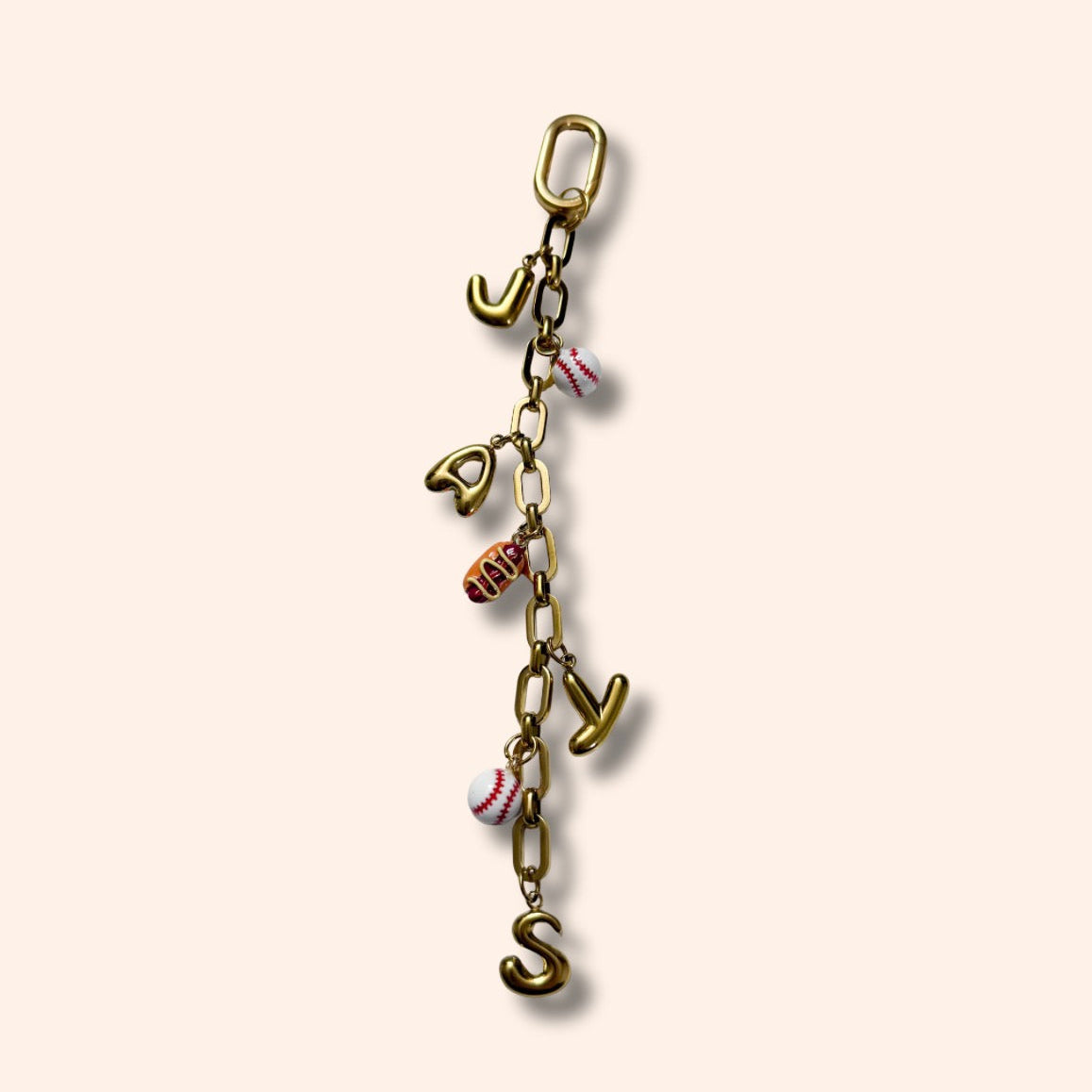Gold charm with letters and small figures on a beige background