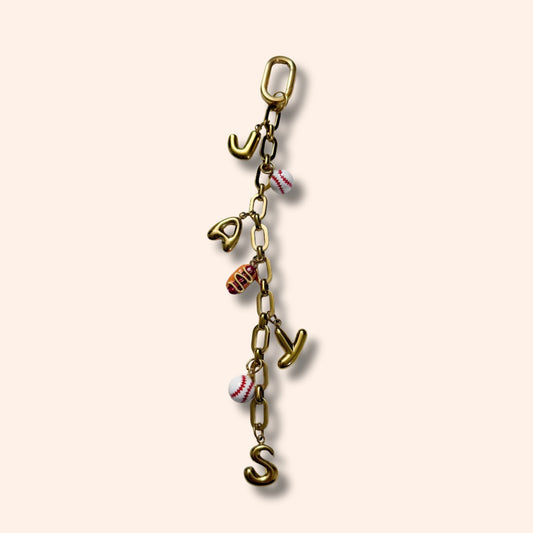 Gold charm with letters and small figures on a beige background