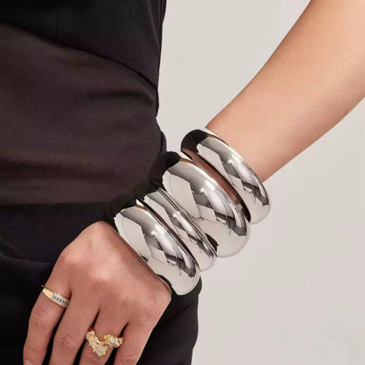 Silver bangles on a wrist with a neutral background