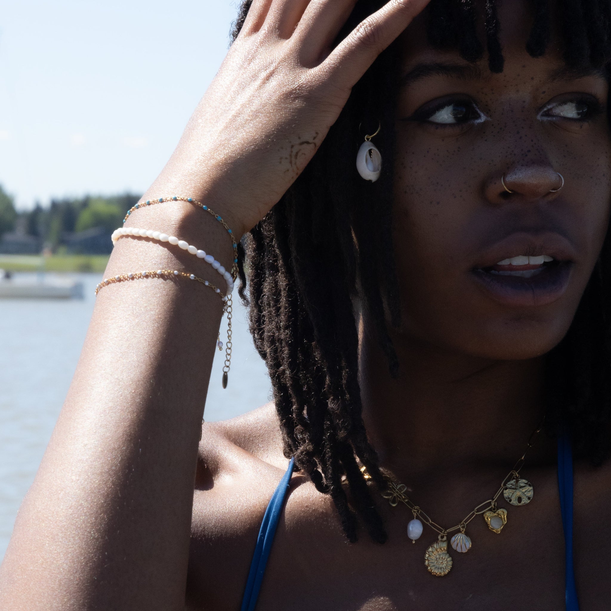 Woman with braided hair and a blue top by a body of water