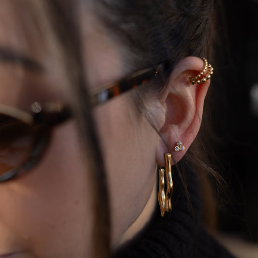 Close-up of a person wearing gold hoop earrings and sunglasses.