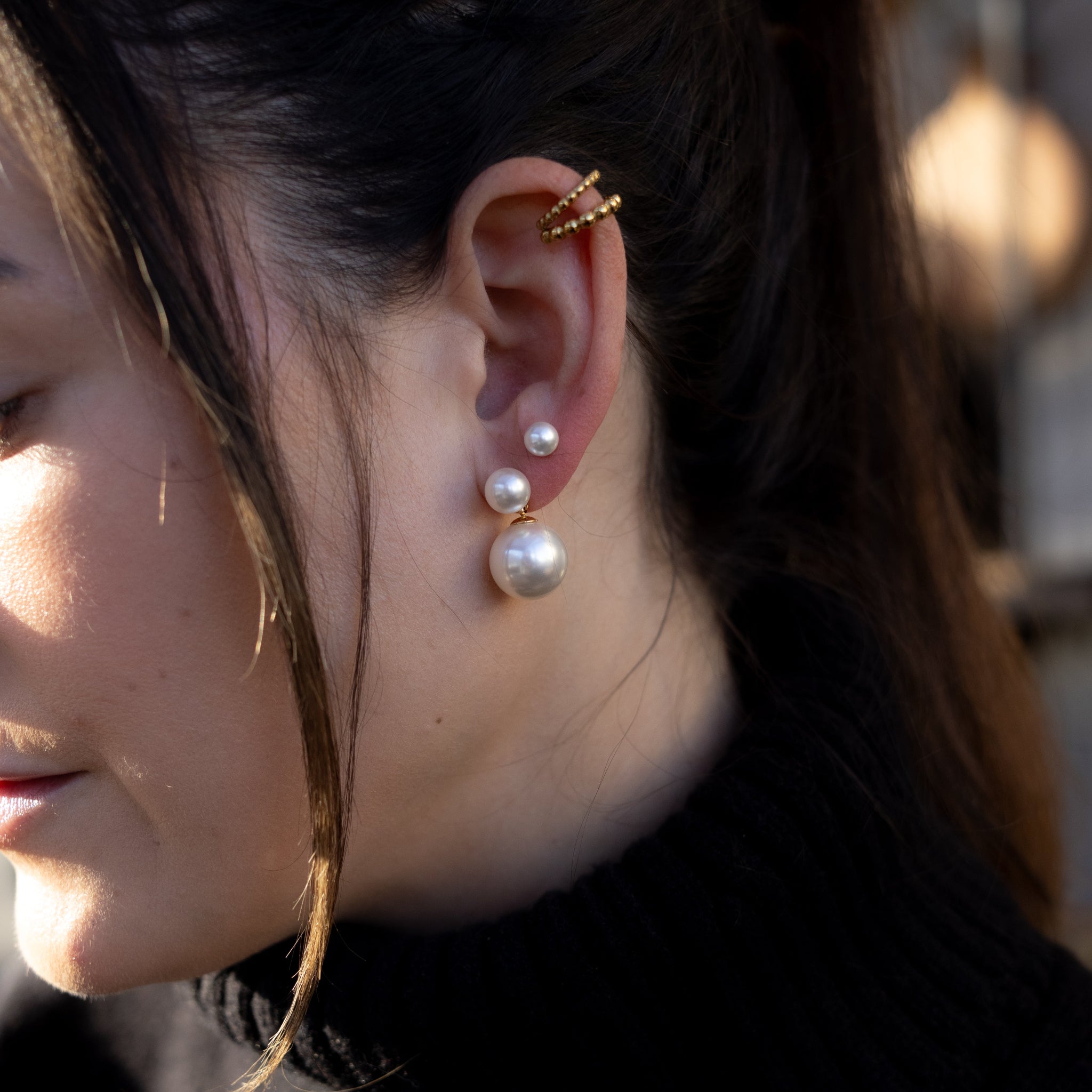 Close-up of a woman wearing pearl earrings with a blurred background