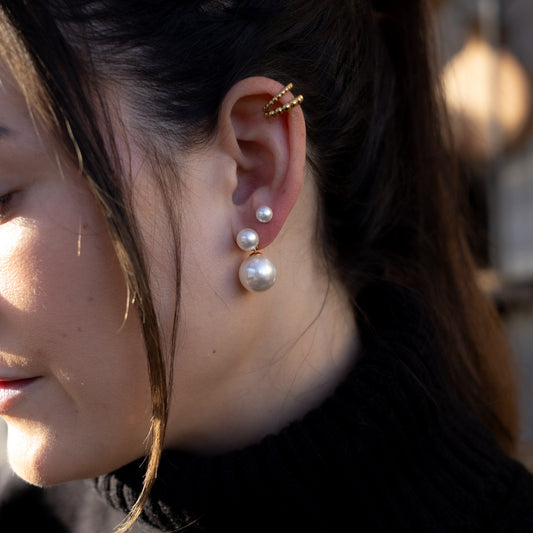 Close-up of a woman wearing pearl earrings with a blurred background