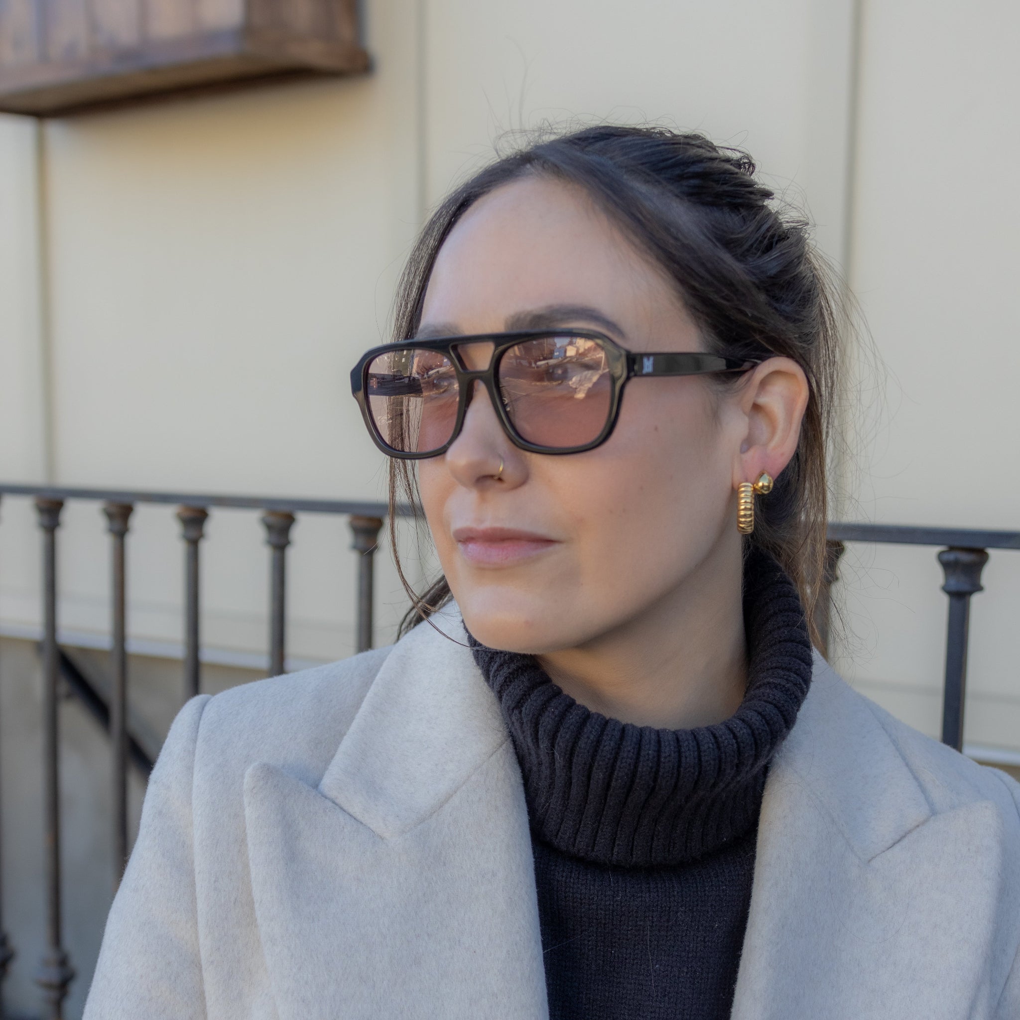 Woman wearing glasses and a light coat outdoors