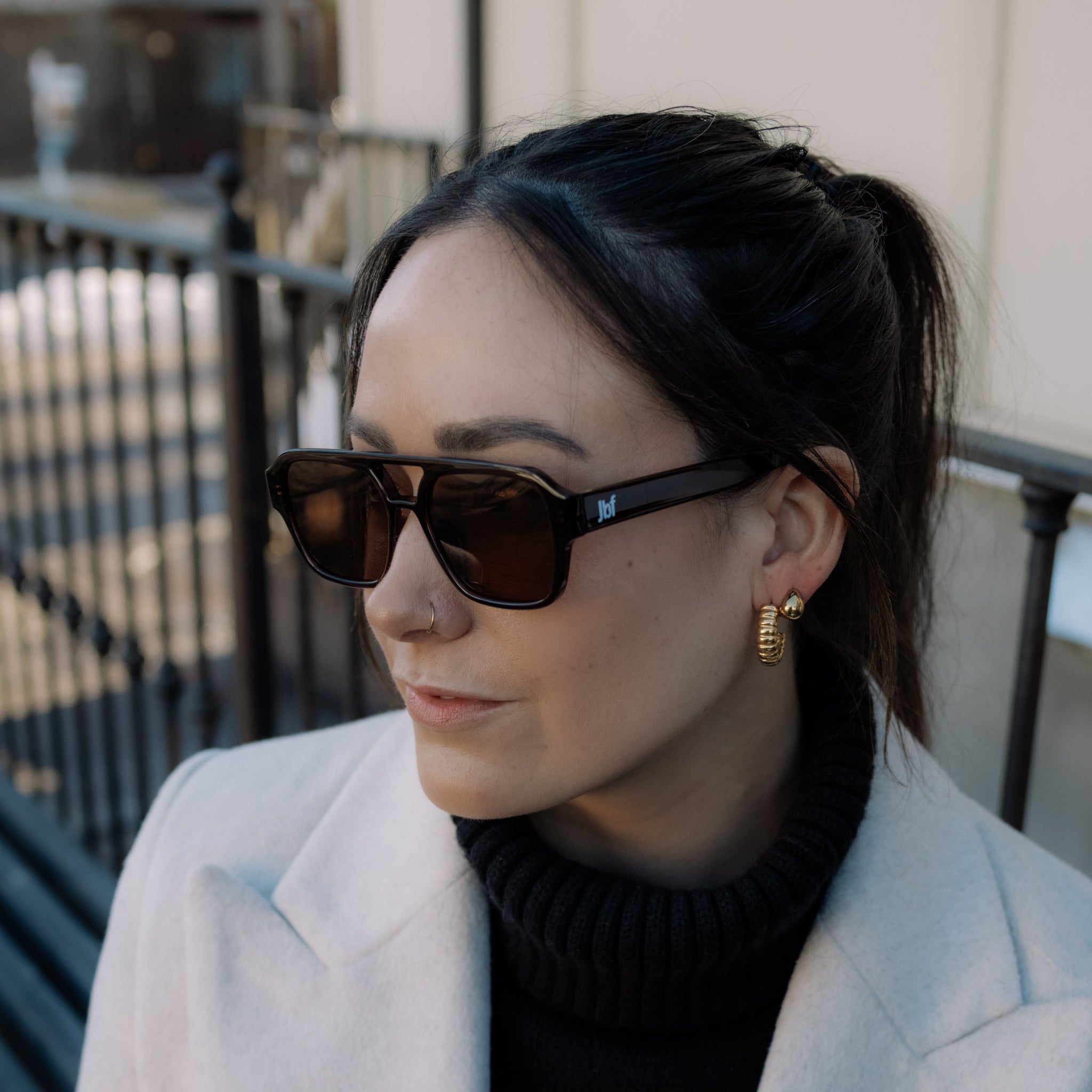 Woman wearing sunglasses and a light coat outdoors