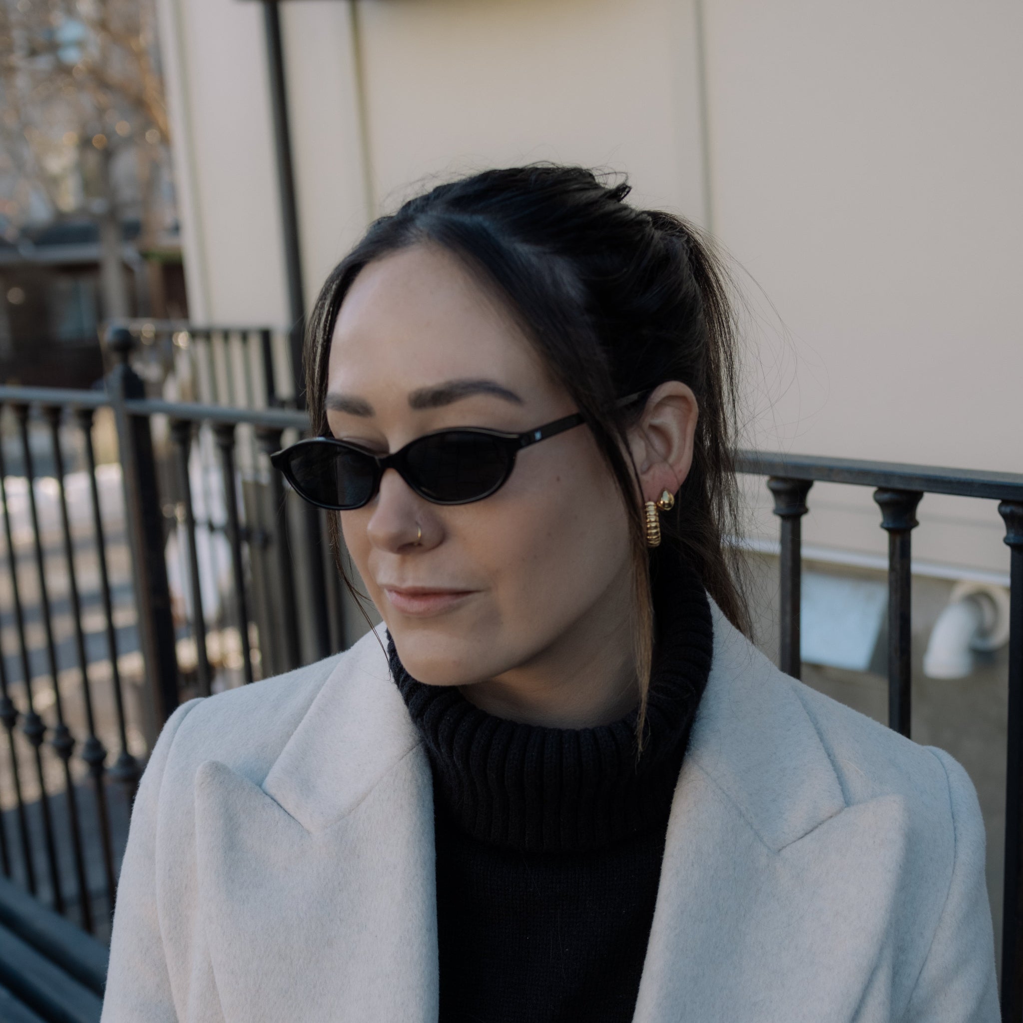 Woman wearing sunglasses and a light coat outdoors