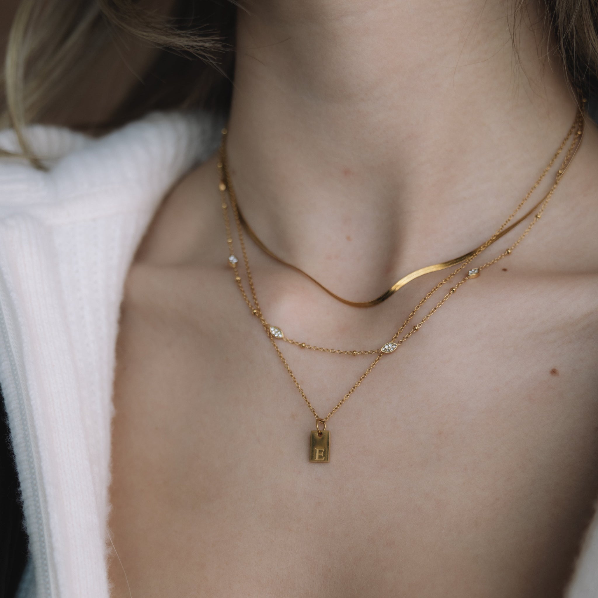 Close-up of a person wearing gold necklaces with a white garment.