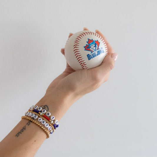 Hand holding a baseball with branding against a plain background