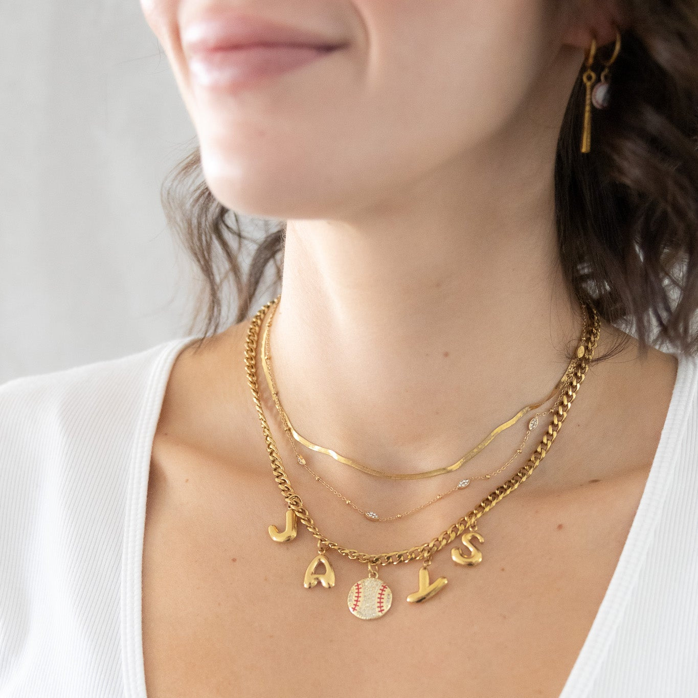 Gold necklaces with charms on a person wearing a white top
