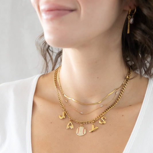 Gold necklaces with charms on a person wearing a white top