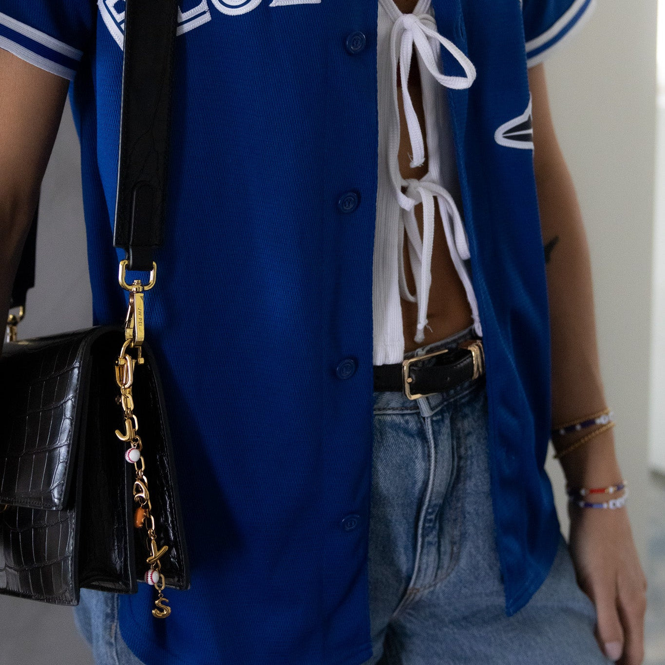 Person wearing a blue letterman jacket with 'BLUE JAYS' text, carrying a black handbag.
