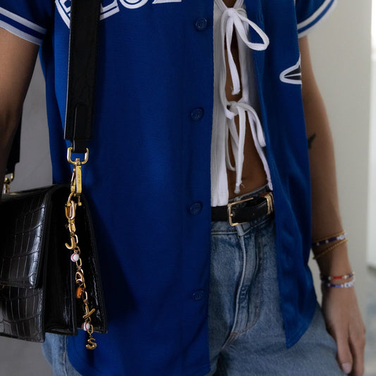 Person wearing a blue letterman jacket with 'BLUE JAYS' text, carrying a black handbag.