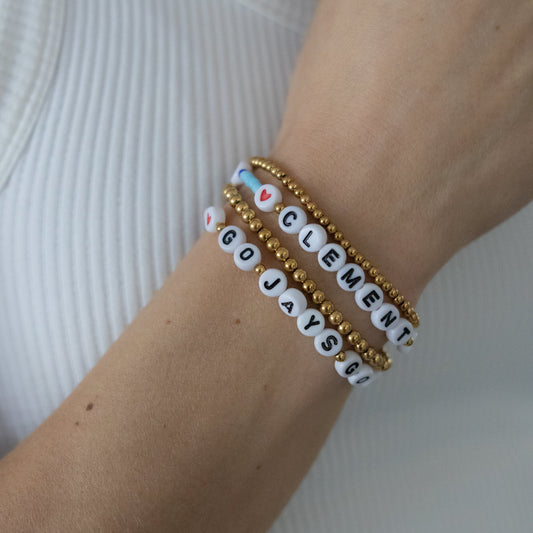 Bracelets with letter beads on a wrist against a white background