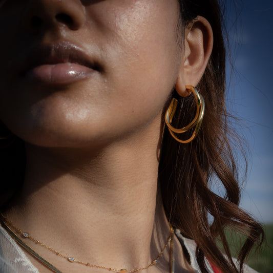 Close-up of a person wearing gold jewelry with a blurred natural background
