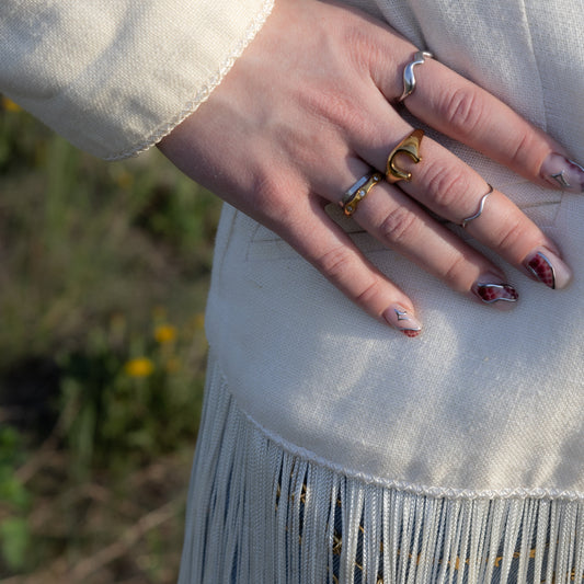 Close-up of a hand with multiple rings on a blurred natural background