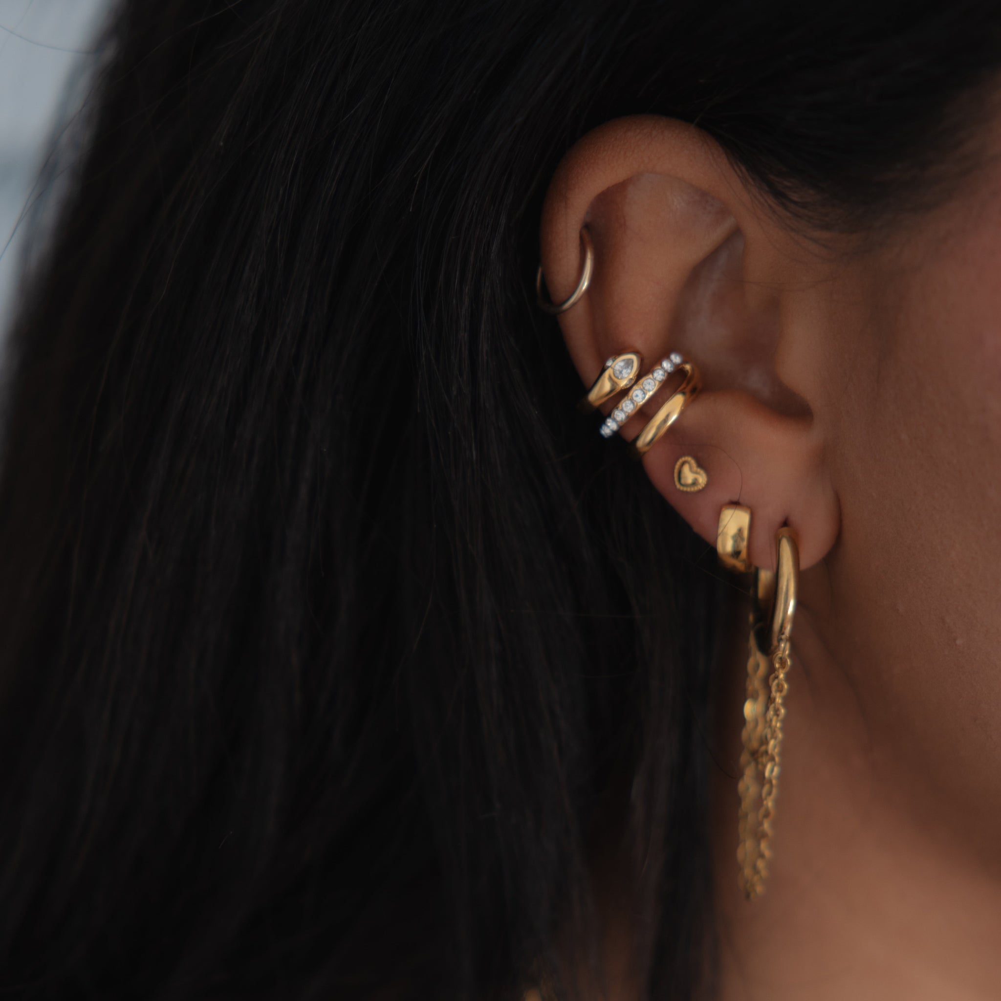 Close-up of an ear with gold earrings and hair.