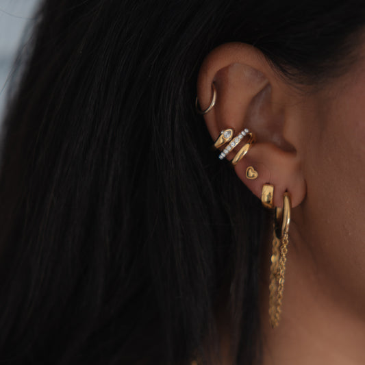 Close-up of an ear with gold earrings and hair.