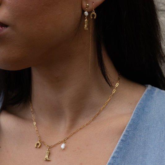 Close-up of a person wearing gold earrings and a necklace with small pendants.