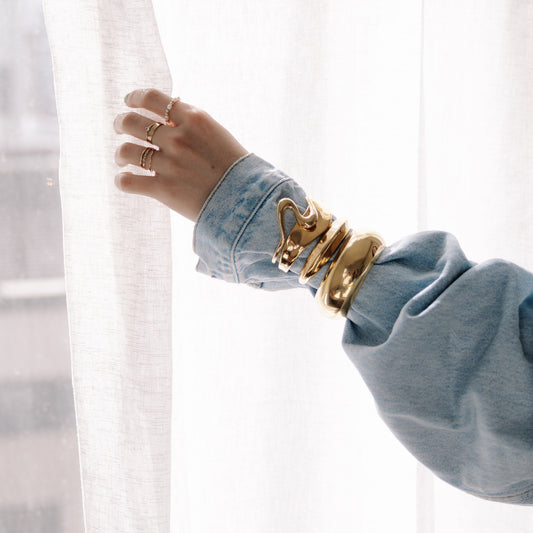 Hand wearing a gold bracelet with denim outfit. 