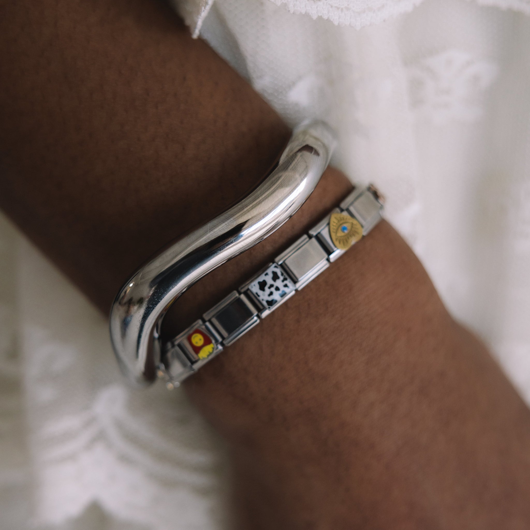 Silver bracelet with embedded stones on a wrist against a white lace background