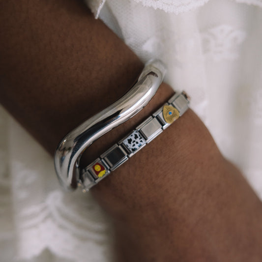 Silver bracelet with embedded stones on a wrist against a white lace background