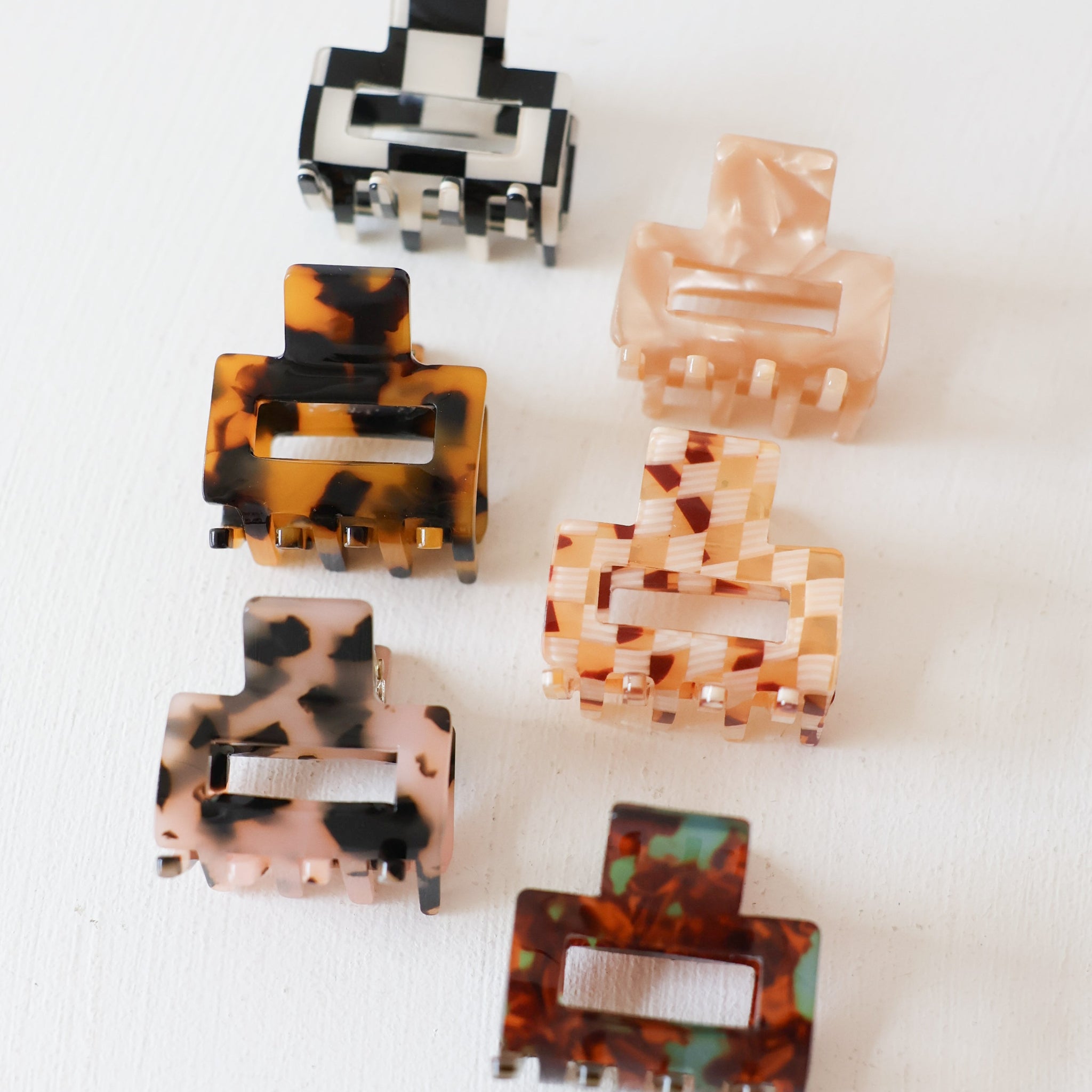Set of six square hair clips with different patterns on a white background