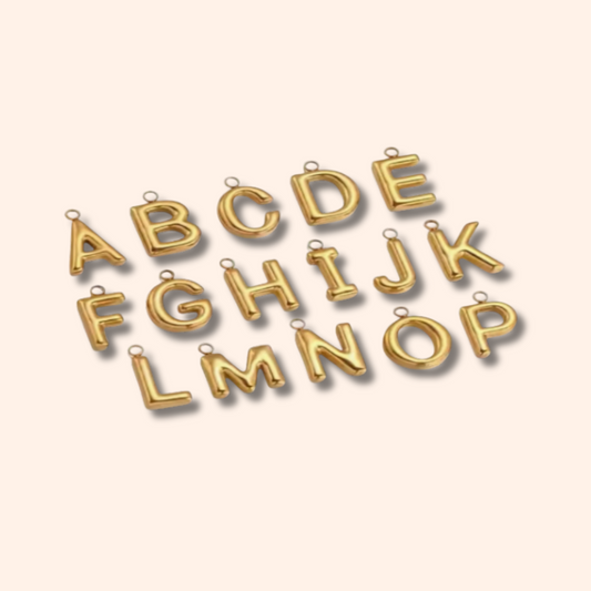 Gold letter pendants arranged in a circular pattern on a beige background