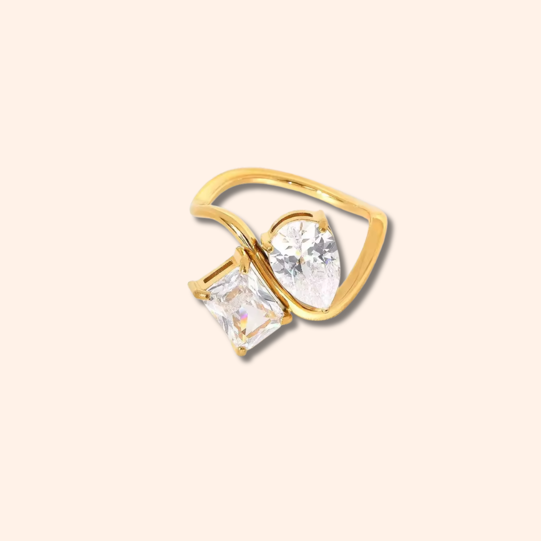 Gold ring with clear gemstones on a beige background