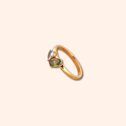 Gold ring with a green gemstone on a beige background