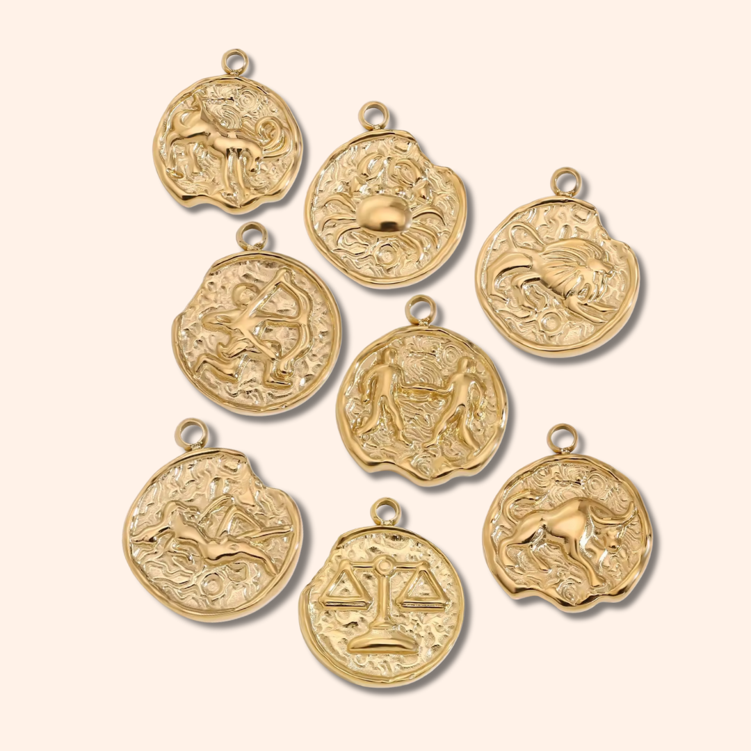 Gold zodiac pendants on a beige background